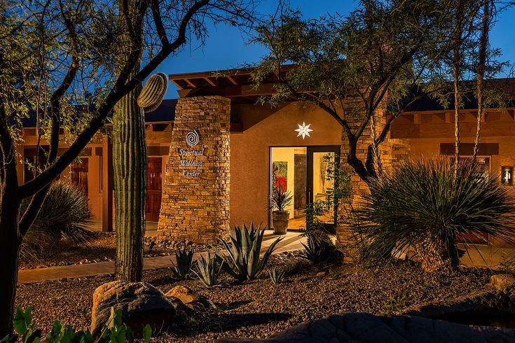 an adobe style home with cactus and cacti in the front yard at night