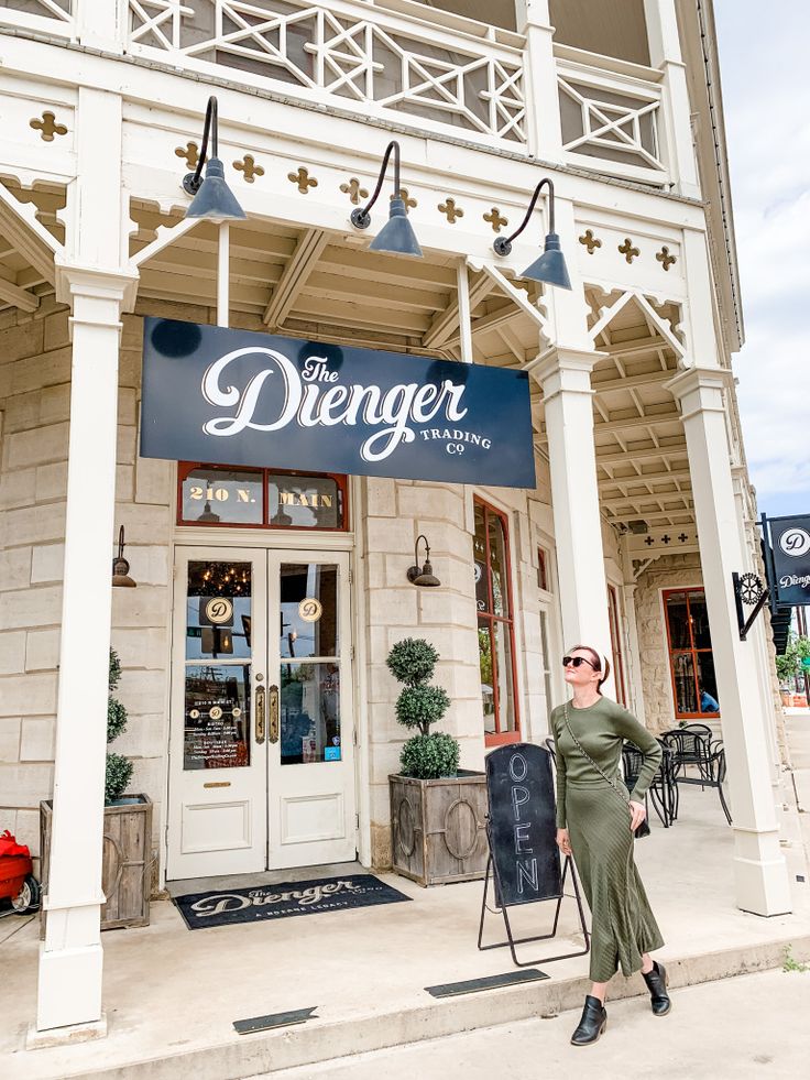 a woman standing in front of a building with a sign that says the delenger