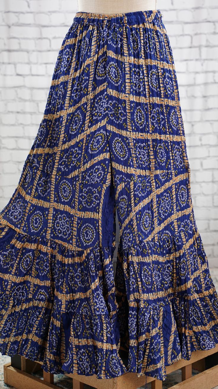 PRODUCT DETAILS These are beautiful Bandhini Palazzos pants that are tiered and have flary hem. The waist has a stretch elastic band with tying strings for a good fit. It is made of paper silk fabric, which has a very good flow. It resembles crushed satin silk. You can wear this with an Indian Kurti or a stylist western top!! Your creativity is the limit with these colorful, printed Palazzo pants! :) Size: One Size Length: 38 inches In seam: 25 inches Waist: expands upto 42 inches Material & Fitted Wide Leg Bottoms With Ruffle Hem, Bohemian Long Skirt With Layered Hem, Bohemian Bottoms With Ruffle Hem, Flowy Long Skirt With Ruffle Hem, Bohemian Bandhani Print Sharara, Bohemian Fitted Sharara With Bandhani Print, Bohemian Fitted Bandhani Print Sharara, Fitted Bohemian Bandhani Print Sharara, Bohemian Tiered Skirt With Ruffle Hem