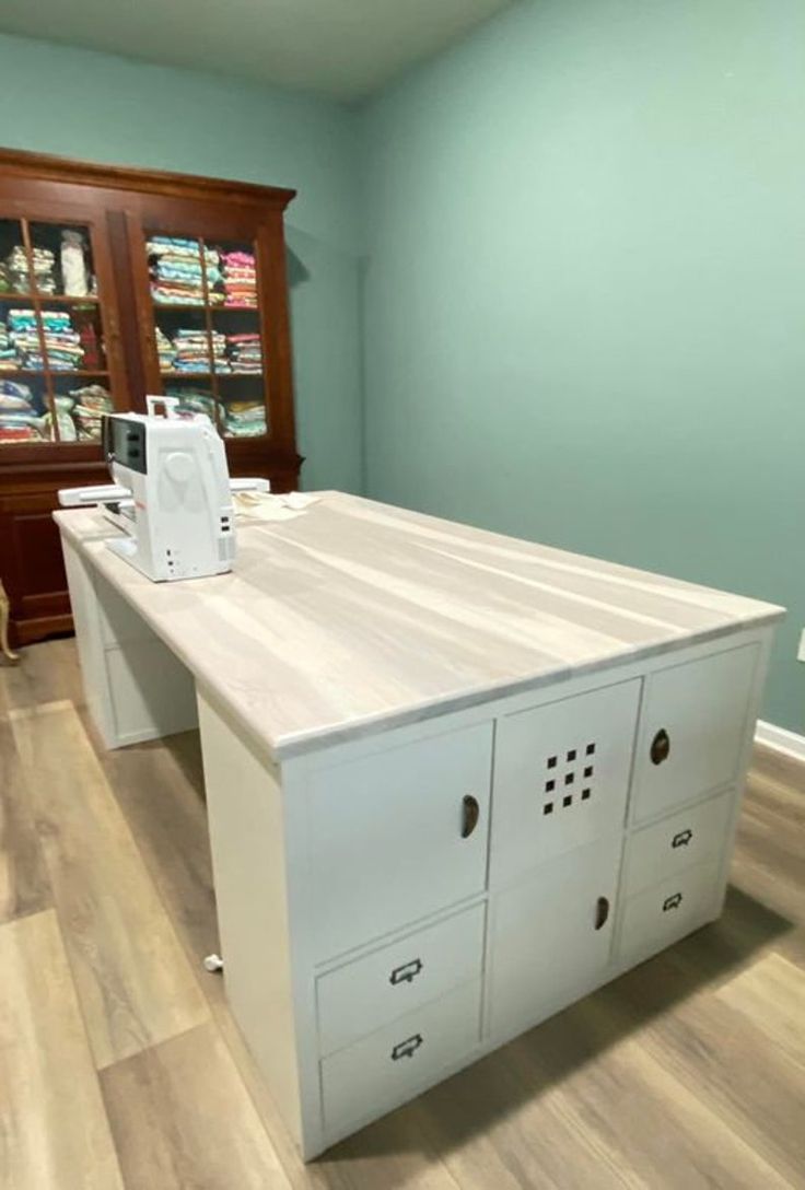 a sewing machine sitting on top of a white cabinet in a room with hardwood floors