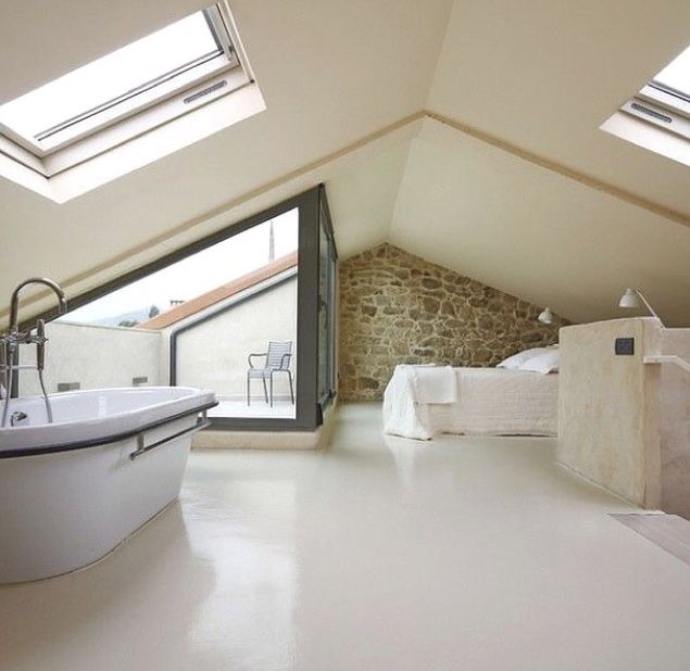 an attic bedroom with skylights and a white bathtub in the middle of it