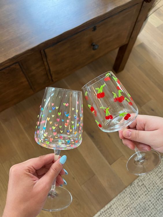 two people holding up wine glasses with confetti on the rims, one is empty