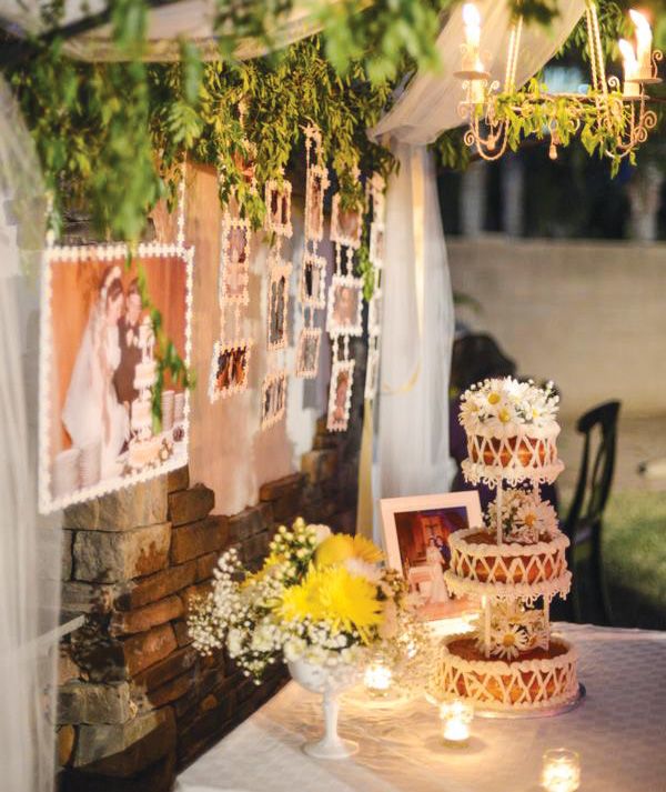 a wedding cake sitting on top of a table under a chandelier filled with flowers