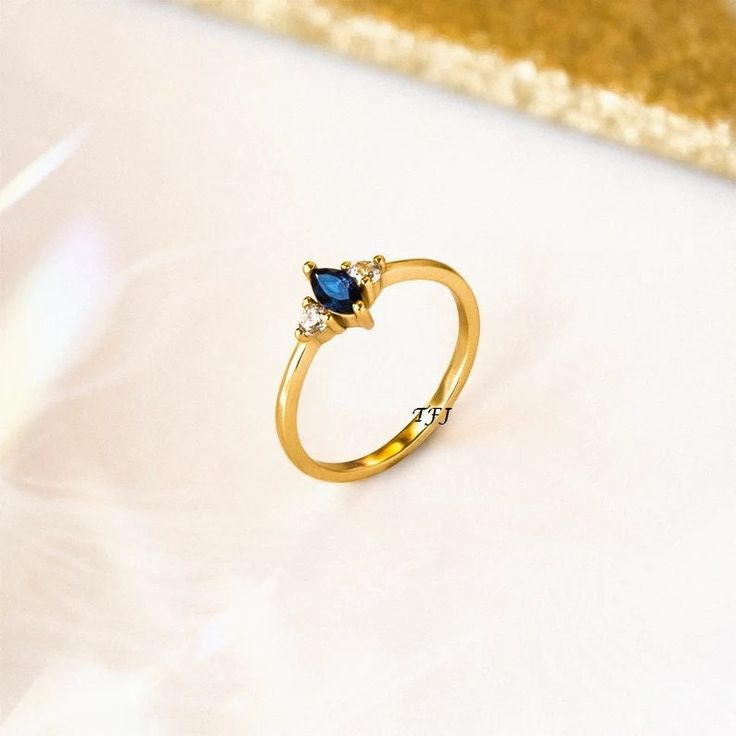 a gold ring with blue and white stones on the side, sitting on a table