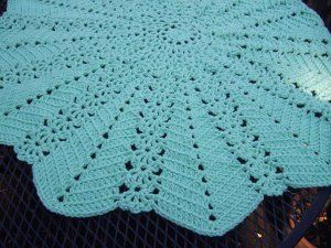 a blue crocheted blanket on top of a table next to a wire fence