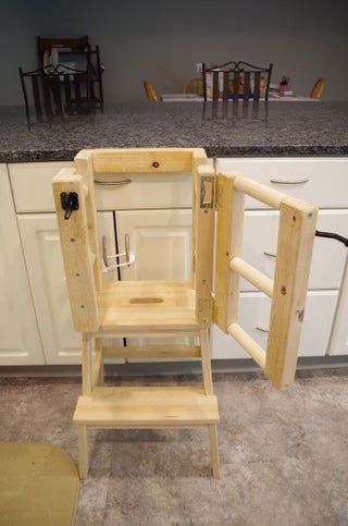 a wooden step stool sitting in the middle of a kitchen next to an open door