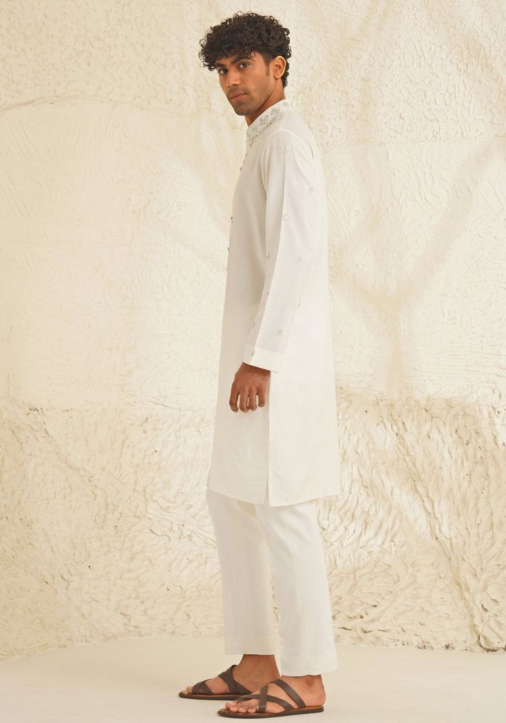 Presenting an exquisite Porcelain White Silk Kurta Set, featuring a sophisticated Chinese collar, elegant metallic silver buttons, and intricate hand-embroidered detailing on the neckline and sleeves. Paired with trendy white pants, this ensemble is perfect for engagements, Roka ceremonies, or puja events, combining timeless elegance with contemporary style. Composition : Dupion Silk Care: Dry Clean Only and Vacuum Storage This product can be customized for sleeves, length and colour Delivery : 4-6 weeks as the product is hand crafted. Check Size Guide or choose MySize for free customisation (All Sizes above XL can be made at 15% additional cost) For more information and sizes please contact fabiliciousfashion@gmail.com or visit our Copenhagen studio. About the Designer : Shreyansh, a dist Elegant Sets With Pearl Embroidery For Diwali, Elegant Semi-formal Sets For Eid, Elegant Unstitched Suit With Naqshi Straight Kurta, Elegant Festive Traditional Wear With Pearl Embroidery, Elegant Naqshi Unstitched Suit For Designer Wear, Elegant Straight Kurta With Set-in Sleeves, Festive Kurta With Set-in Sleeves, Elegant Embroidered Straight Kurta Set, Elegant Lawn Suit With Dabka For Wedding