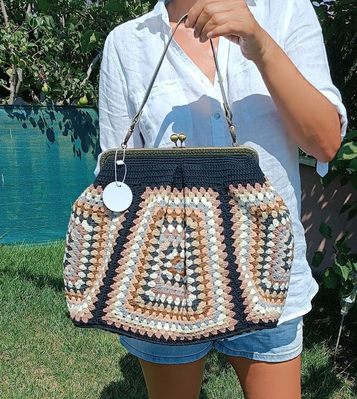 a woman holding a crocheted purse in her hands