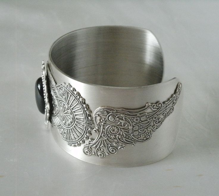 This beautiful silver plated cuff bracelet has a black onyx stone set on silver plated embellishments and silver plated gothic wings on the sides. Adjustable. Bohemian Cuff Jewelry For Formal Occasions, Metal Bangle With Jewels, Elegant Engraved Stainless Steel Cuff Bracelet, Unique Metal Bracelets With Jewels, Unique Engraved Metal Jewelry, Formal Silver Stainless Steel Bangle, Ornate Metal Bracelet Jewelry, Elegant Metal Cuff Bracelet With Oxidized Finish, Elegant Oxidized Metal Cuff Bracelet