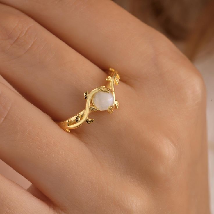 Vintage Moonstone Statement Ring: The Perfect Gift for Mom This stunning moonstone statement ring is the ideal gift for your beloved mother. Crafted with a vintage flair, it showcases a natural moonstone that radiates a captivating allure. The ring features a beautiful gold leaf 'mama' design, symbolizing the unconditional love between a mother and child. Made with high-quality silver gemstone jewelry and a gold filled ring band, it exudes elegance and sophistication. Surprise your mom with this exquisite piece that she will cherish for years to come. Style -1 ; moonstone size: 8 mm Style -2 ; moonstone size: 5 mm ♥ Product Specifications ♥ Material : Sterling Silver is an 14k gold-filled (A 0.5 micron thick layer of solid gold on Sterling Silver) Ring Wire Thickness : 0,05" - 1,4 mm Ring Elegant Gold Moonstone Ring With Natural Stones, Spiritual Opal Birthstone Ring, Elegant Moonstone Ring As A Birthstone Gift, Elegant Moonstone Birthstone Ring Gift, Elegant Moonstone Ring With Natural Stones For Anniversary, Elegant Moonstone Open Ring Birthstone, Elegant Moonstone Ring For Anniversary, Delicate Ring For Mother's Day, Delicate Mother's Day Ring