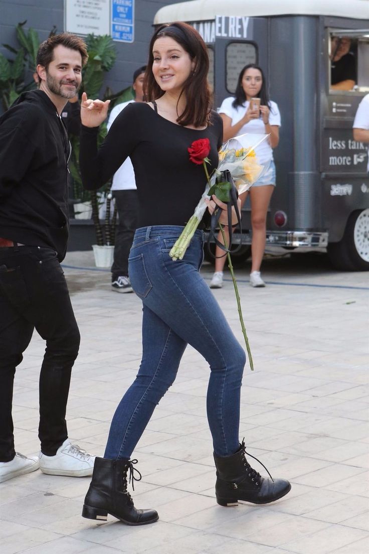 a man standing next to a woman holding a rose and pointing at the camera with both hands