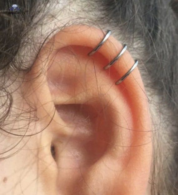 an ear is shown with three thin silver wires