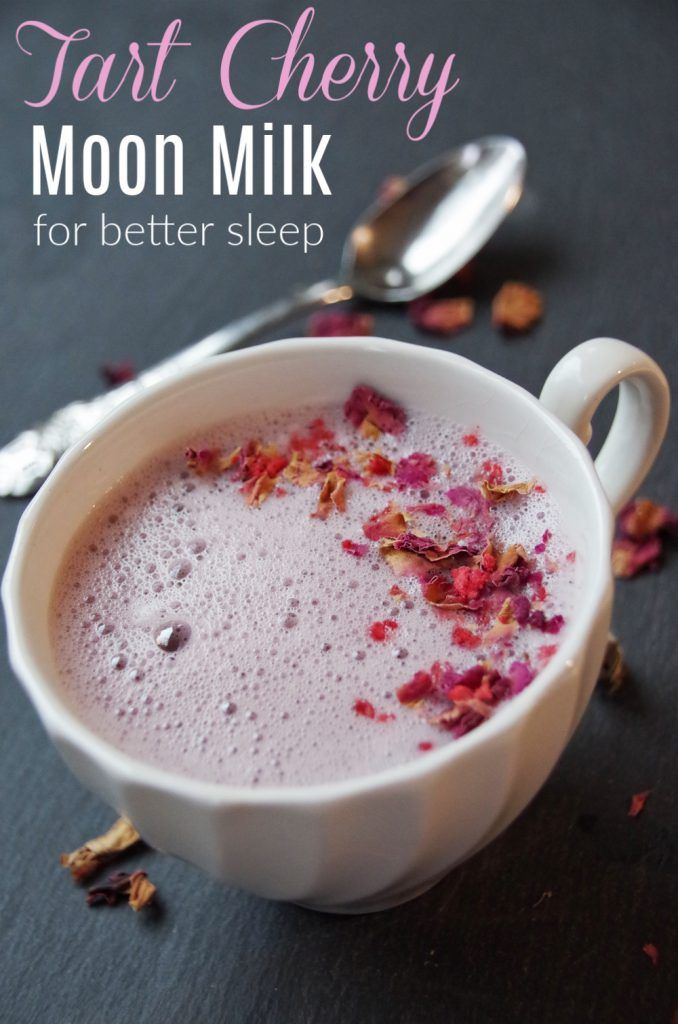 a white bowl filled with milk next to a spoon and rose petals on the table