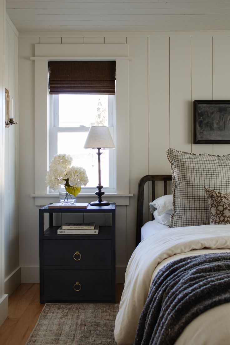 a bed sitting next to a night stand with a lamp on it's side