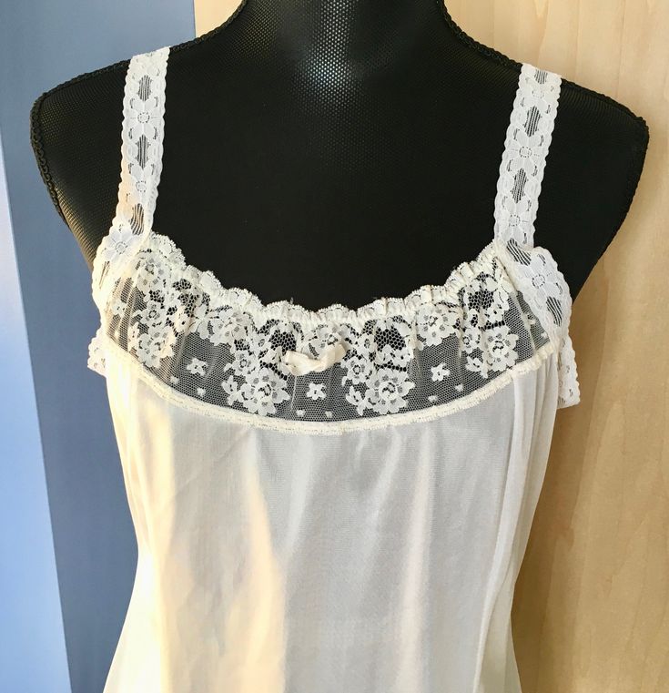 "This white nylon slip by Greenco Maid has lace straps and neckline. There is also lace trim at the hem. The straps are elastic lace but not adjustable. It is a size 38 with these measurements: Bust: 38\" Waist: 36\" Hips: 46\" Shoulder to hem: 40\" Strap length: 6\" Our items are in good condition. Should there be undue wear, something missing or inoperable it will be noted in our text and there will be a photo highlighting such. We add new items regularly and appreciate you taking a look." Summer Lace Camisole With Contrast Lace, White Camisole With Contrast Lace For Summer, White Contrast Lace Camisole For Summer, White Camisole With Contrast Lace, Stretch Lace Camisole With Straps, Lace Camisole With Straps, Sleeveless, White Lace Contrast Camisole, White Contrast Lace Cami Camisole, White Contrast Lace Camisole