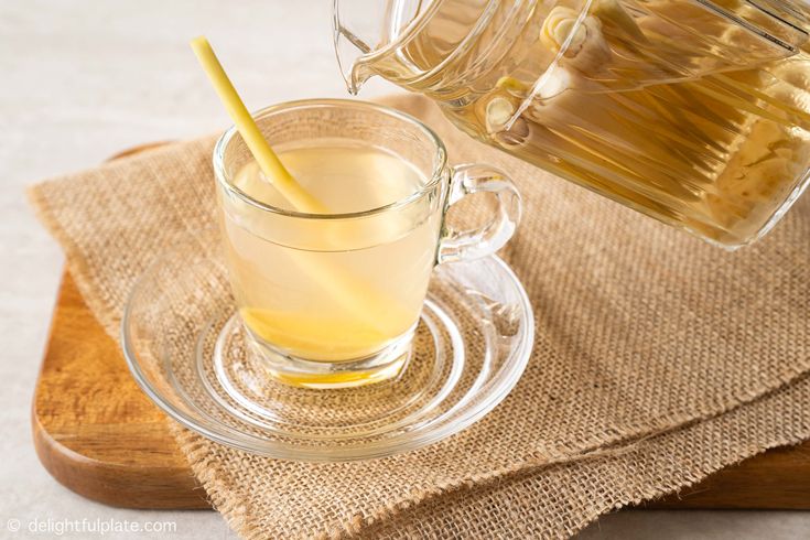 a glass cup filled with liquid next to a teapot and spoon on top of a wooden tray