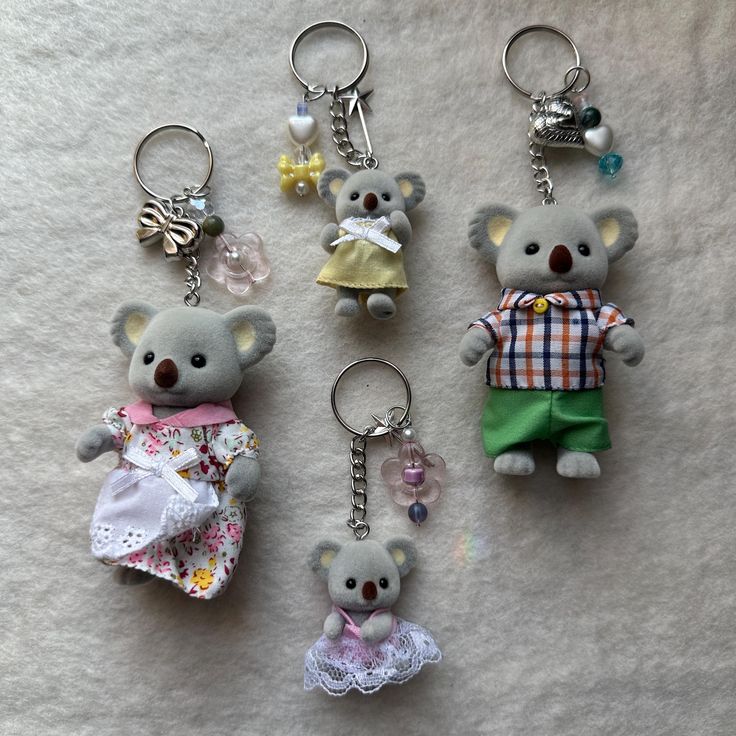 four key chains with teddy bears on them sitting next to each other in different outfits