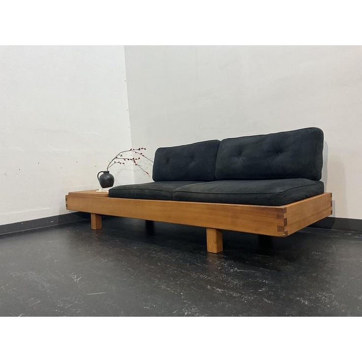 a black couch sitting on top of a wooden floor next to a vase with flowers