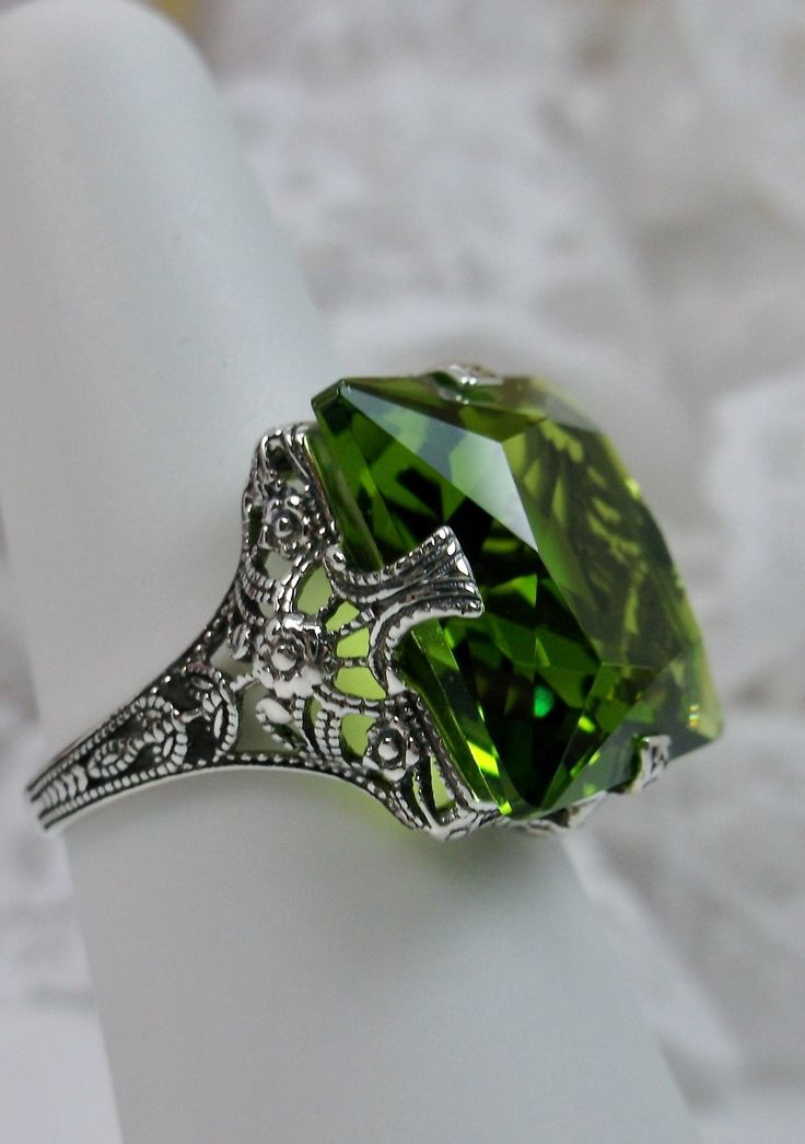 Simulated Green Peridot Ring Description SquareVic Design#77 {Made to Order} This is a brand new Victorian era reproduction floral filigree ring in sterling silver. The rare filigree ring is set with a high-quality simulated peridot. The gemstone is 15mm (about 9/16th of an inch) in length and 15mm in width. The rings stand about 8mm off the finger. The inside of the band is marked 925 for sterling. This is a lovely new, well-made ring and it is ready to wear. A ring gift box included and all ri Green Crystal Ring With Stones As A Gift, Art Deco Green Jewelry With Accent Stones, Green Art Deco Jewelry With Accent Stones, Elegant Large Stone Green Emerald Ring, Elegant Peridot Ring Jewelry, Elegant Green Emerald Ring With Large Stone, Elegant Green Crystal Ring With Accent Stones, Elegant Green Crystal Ring For May Birthstone, Elegant Large Green Emerald Ring