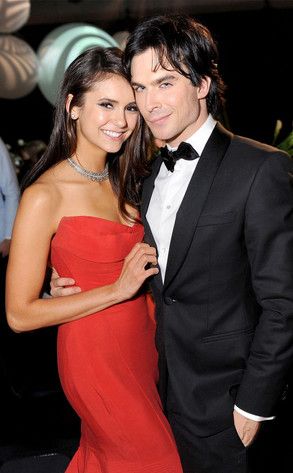 a man in a tuxedo standing next to a woman wearing a red dress