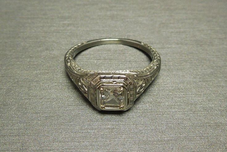 an antique silver ring with a square cut diamond in the center and filigrees