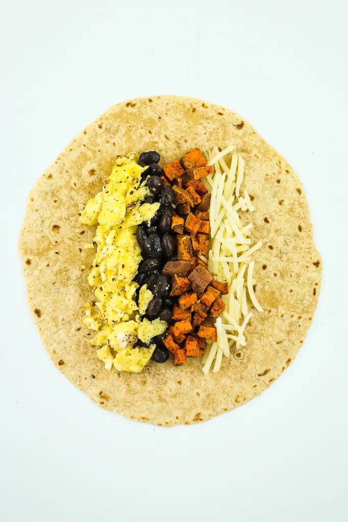 a tortilla filled with eggs, cheese and black beans on a white background