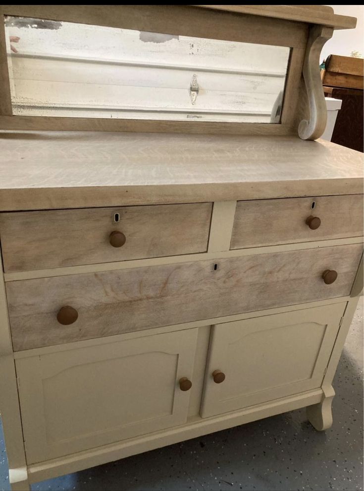 an old dresser is painted white and has drawers on each side, with knobs at the bottom