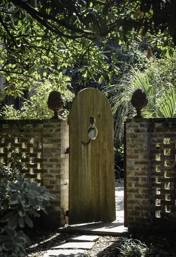 an open wooden gate in the middle of a garden