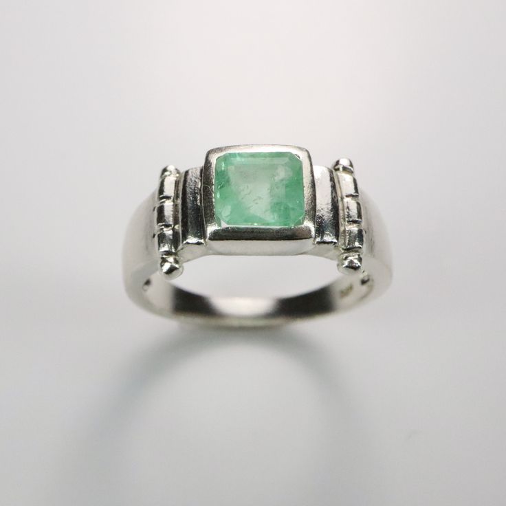 an image of a ring with a green stone in the center on a white background