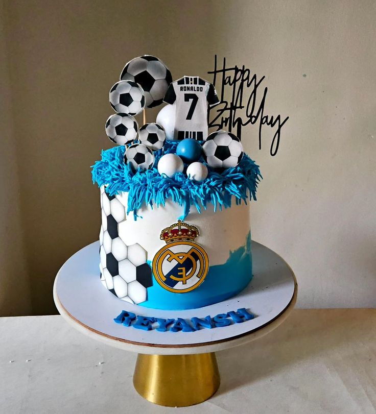 a birthday cake with soccer balls on top and blue decorations in the bottom tiers