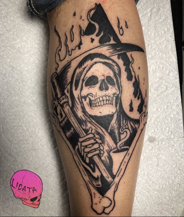 a man's leg with a skull holding a cross and a hat on it