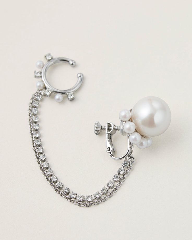 This modern and playful 4-way chained earring is inspired by this season's gothic rock theme. Cast from silver plated brass with delicate faux pearls and luminous crystals. The ear cuff is linked to the bottom pearl earring with chains, it can be detached and worn as a nose ring for elevating a glam punk look. You can also wear the pearl earring as a single piece with dangling chains. Fine Jewelry Clip-on Earrings For Party, Elegant Diamond Ear Cuff As Gift, Timeless Single Earring For Party, Clip-on Sterling Silver Jewelry In White Gold, Clip-on White Gold Sterling Silver Jewelry, Sterling Silver Clip-on Jewelry In White Gold, White Clip-on Diamond Jewelry, Elegant Dangle Ear Cuff For Wedding, Elegant Clip-on Ear Cuff