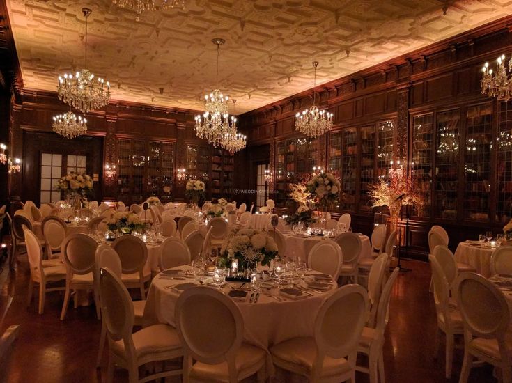 a dining room with tables and chairs set up for a formal function in front of bookshelves