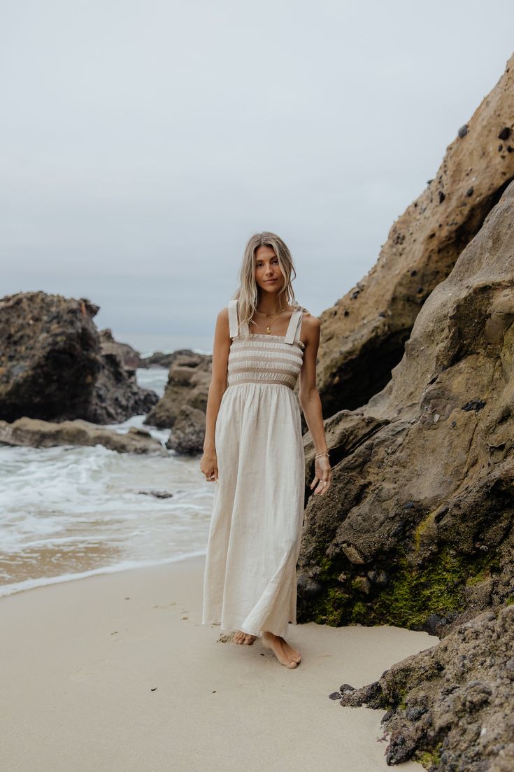 The smocked dress that swept us off our feet! The prettiest tie straps and smocked bodice makes for the comfiest and cutest dress! Have you ever seen a cuter dress? Fits true to size. Model Info: Taylor is 5'9 wearing size Small. Fabric Info: 80% linen 20% cotton Beige Ruffled Strap Dress For Beach, Beige Beach Dress With Ruffled Straps, Bohemian Smocked Dress With Ruffled Straps, Summer Cream Maxi Dress With Smocked Back, Cream Maxi Dress With Smocked Back For Summer, Beige Beach Dress With Smocked Bodice, Beige Beach Dresses With Smocked Bodice, Cream Dress With Smocked Bodice For Vacation, Beige Dresses With Smocked Bodice For Beach