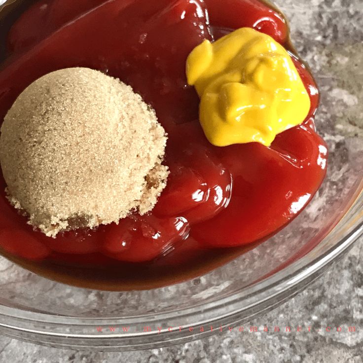 a bowl filled with ketchup and mustard next to a small yellow object on top of it