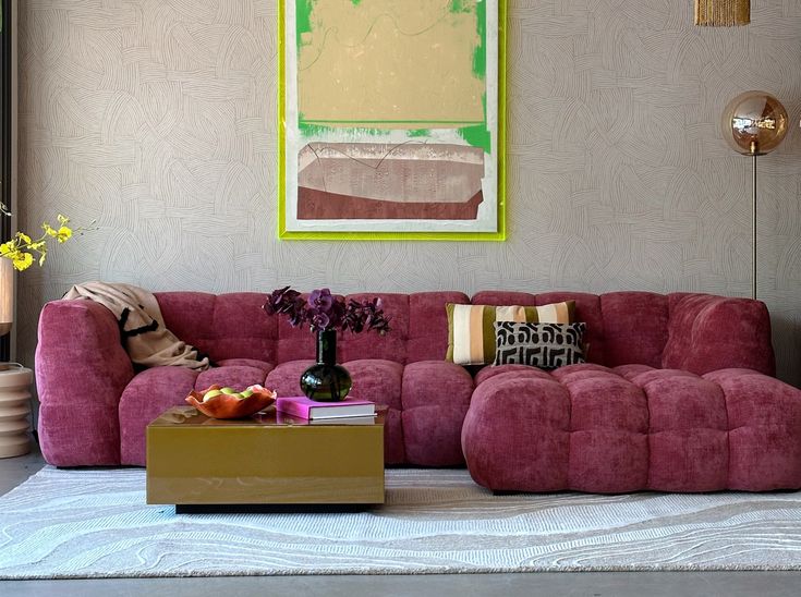 a living room with pink couches and colorful art on the wall behind it,