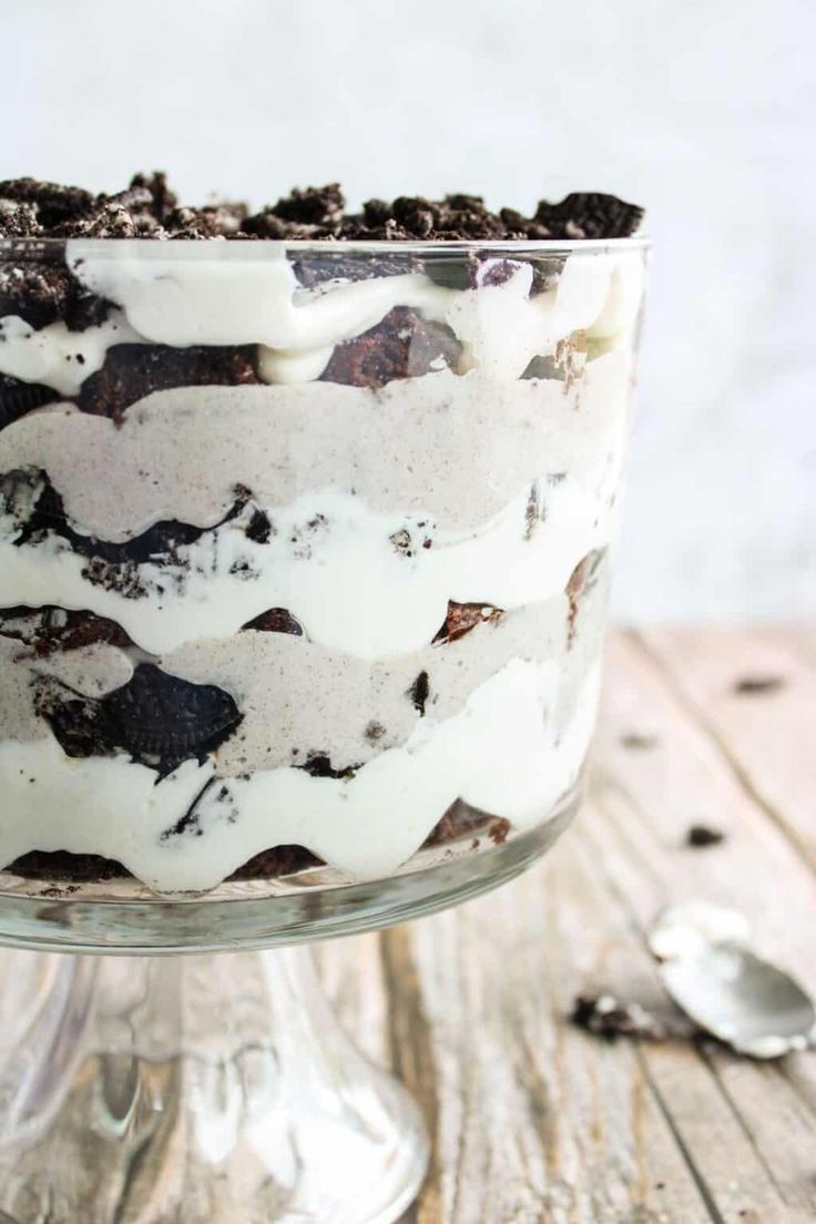 an oreo cookie and cream trifle in a glass dish on a wooden table