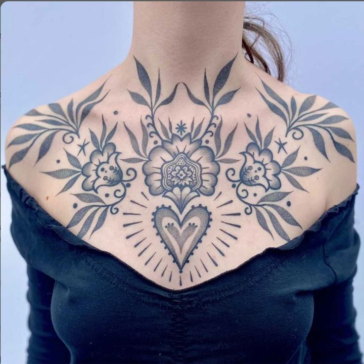 a woman's chest with flowers and hearts tattooed on the back of her neck