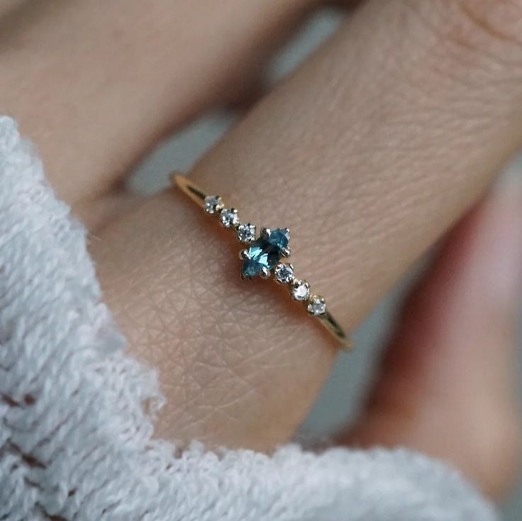 a woman's hand with a ring on it that has three stones in the middle