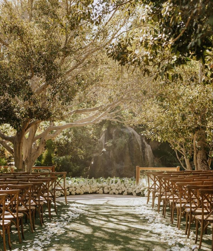 an outdoor ceremony set up with wooden chairs