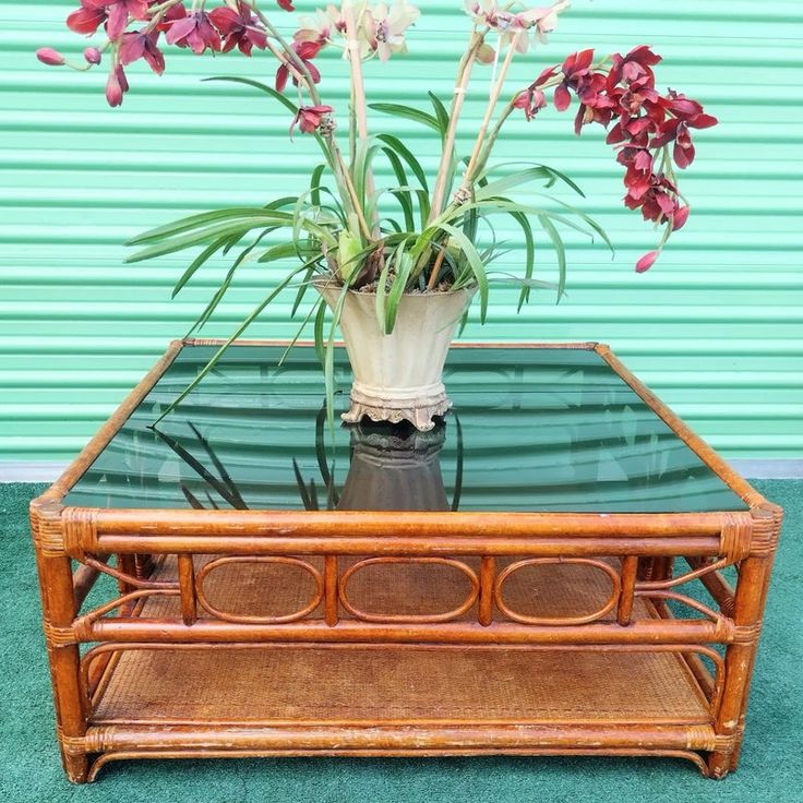 a glass top coffee table with flowers in it on green carpeted floor next to blue wall