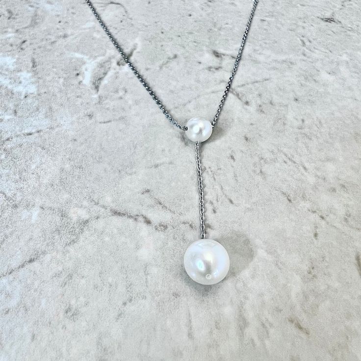 Sterling silver pearl lariat pendant necklace featuring 2 genuine round white freshwater pearls. The larger pearl measures approximately 8.5-9 mm. L: Chain is 18 inches long. Birthstone: June. Condition: Excellent, Brand New. - 14 day return policy, no questions asked. - Free insured shipping in the US. - International shipping available. Note: All items have been appraised and inspected by a jewelry specialist and certified gemologist (GIA GG). All diamond and gemstone gradings are done under G White Sterling Silver Lariat Necklace For Anniversary, Sterling Silver Lariat Pearl Necklace With Pendant, Adjustable White Lariat Necklace With Pearl Pendant, White Adjustable Lariat Necklace With Pearl Pendant, White Pearl Pendant Lariat Necklace, Sterling Silver Lariat Necklace With Pearl Pendant, Sterling Silver Pearl Drop Lariat Necklace As Gift, Sterling Silver Lariat Necklace With Pearl Drop As Gift, White Lariat Necklace With Pearl Pendant