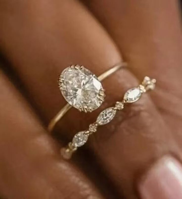 a woman's hand holding a ring with a pear shaped diamond on top of it