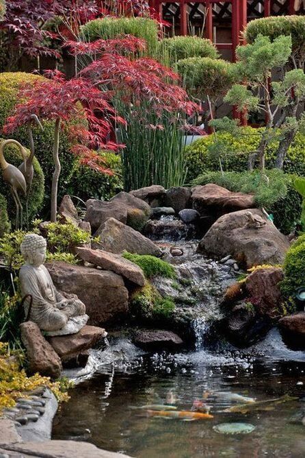 a small pond surrounded by rocks and trees with goldfish swimming in the water below