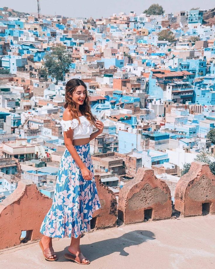 a woman standing in front of a blue city with lots of buildings on the other side