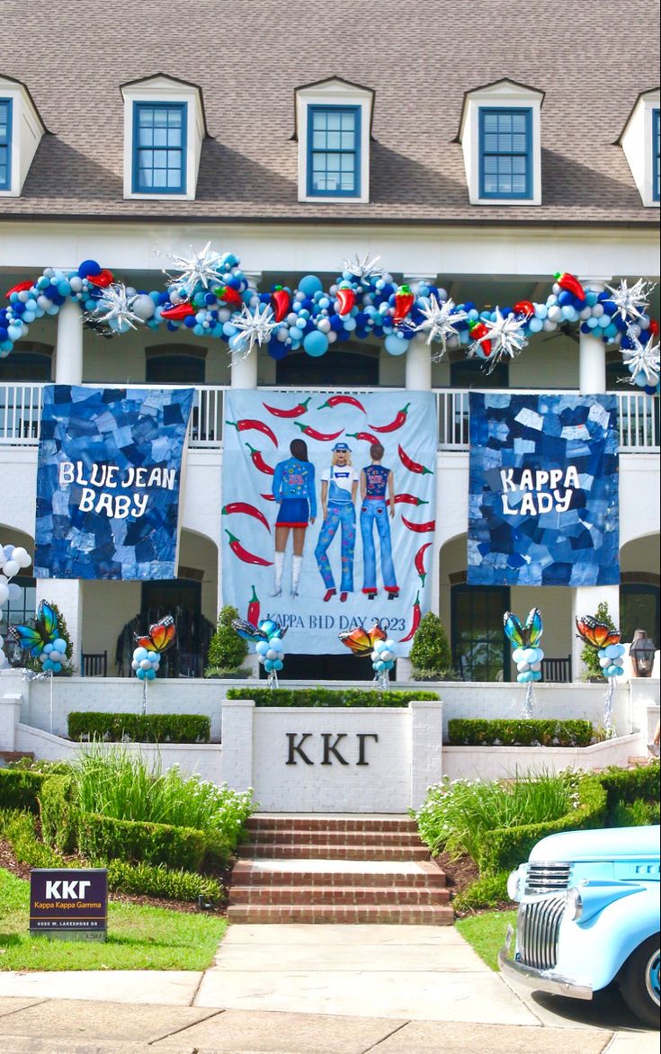 a blue car parked in front of a large building with decorations on it's side