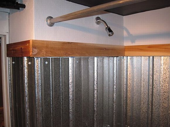 a bathroom with a sink, toilet and shower head mounted on the wall above it