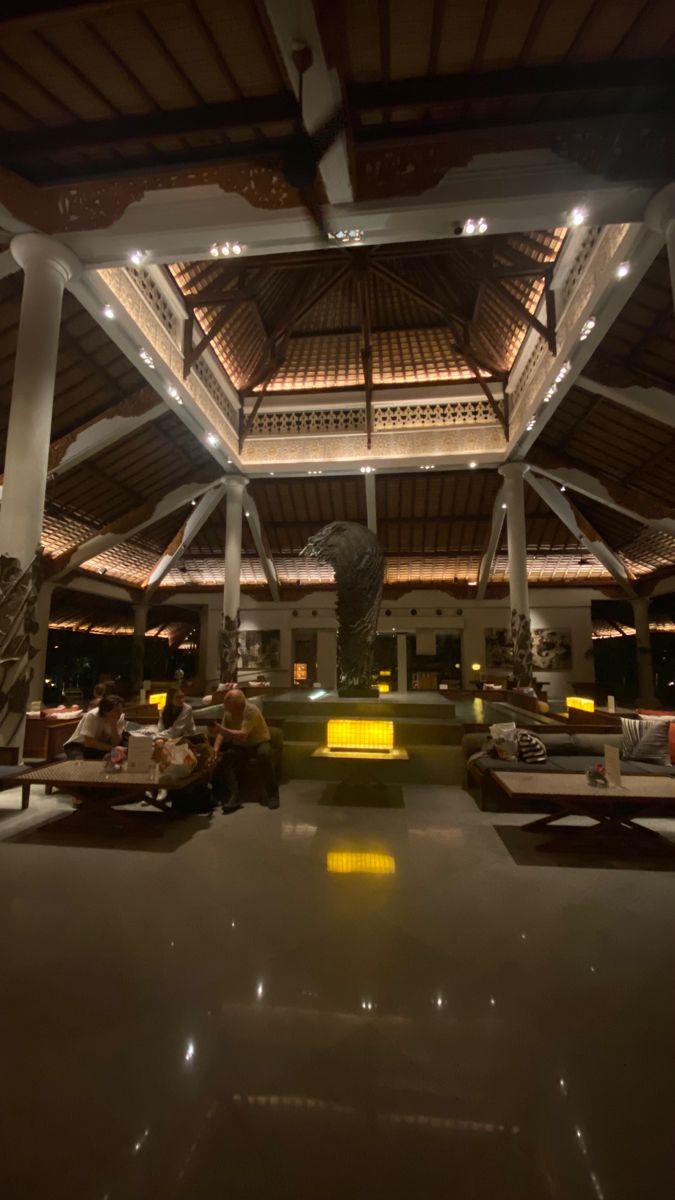 the inside of a building with people sitting on benches and tables in front of it