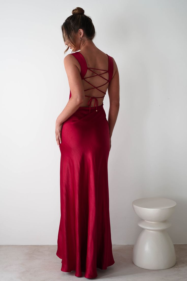 This gown is your perfect choice for debs, prom or any formal event. A look that blends classic glamour with contemporary style. Designed for timeless allure and effortless sophistication. Featuring a graceful cowl neckline and thick shoulder straps, this dress offers a flattering, structured fit. The sultry thigh-high slit adds a bold, modern touch, while the luxurious satin fabric drapes beautifully to enhance your silhouette. Highlights Stunning red gown with cowl neckline Soft satin material Lace Up Formal Dress, Wine Red Maxi Dress, Uk Formal Dresses, Valentines Formal Dresses, Red Revenge Dress, Red Maxi Dress Formal, Val Dresses, Red Silk Dress Long, Wedding Guest Dress Burgundy