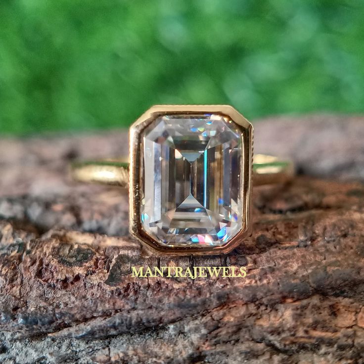 an emerald colored diamond sits on top of a piece of wood